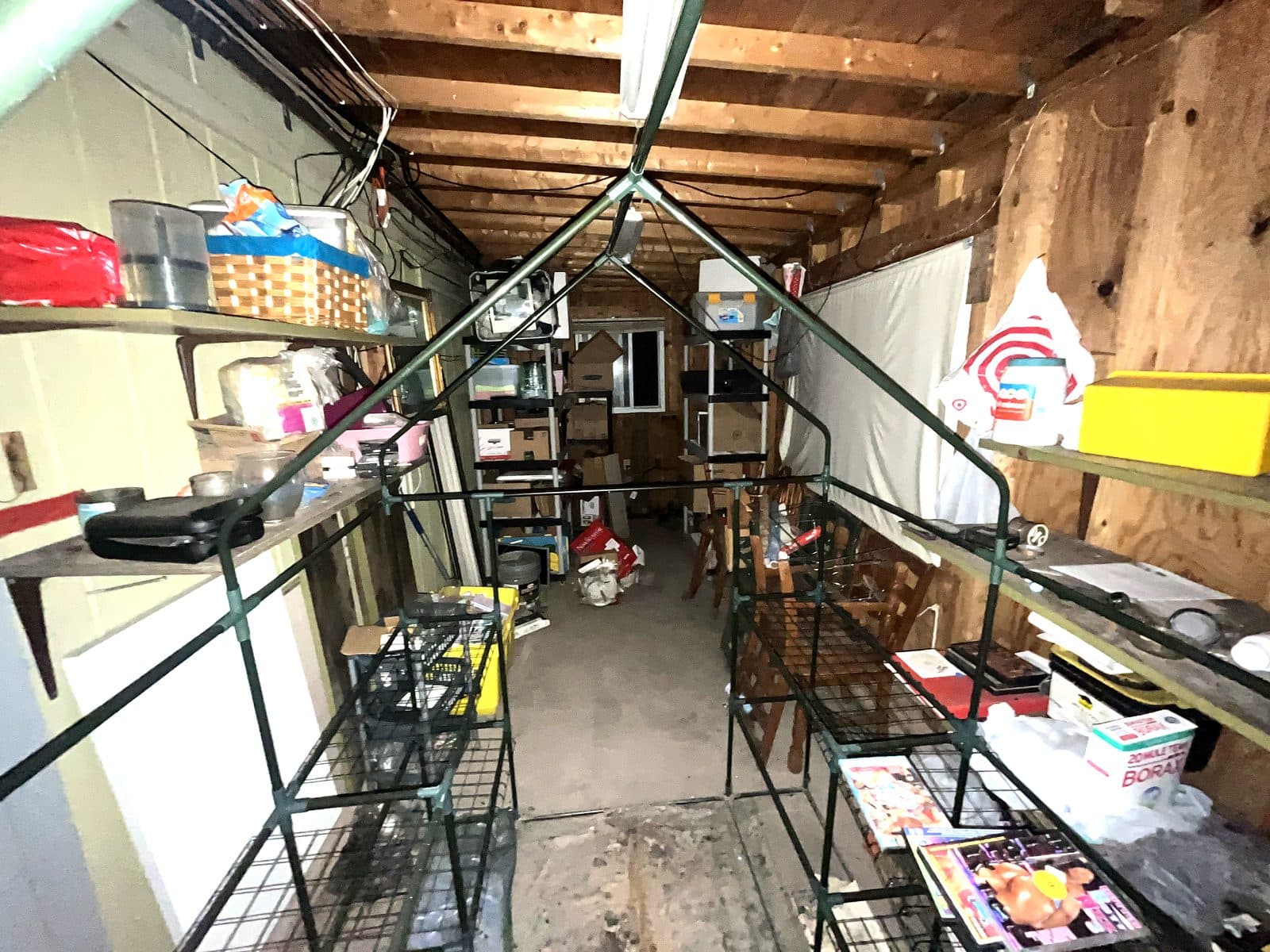 Storage building packed with shelving, bins and household items up to the open rafters