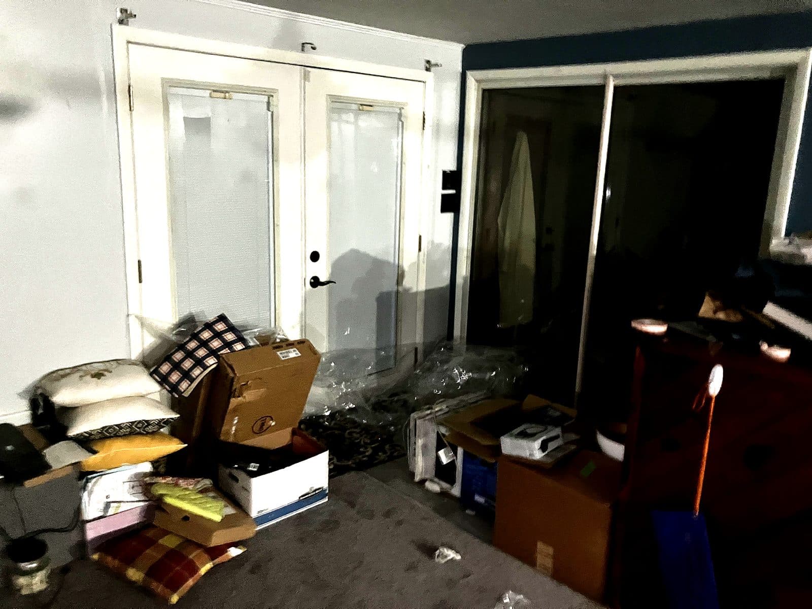 Living room with moving boxes, pillows and stacked belongings covering the floor