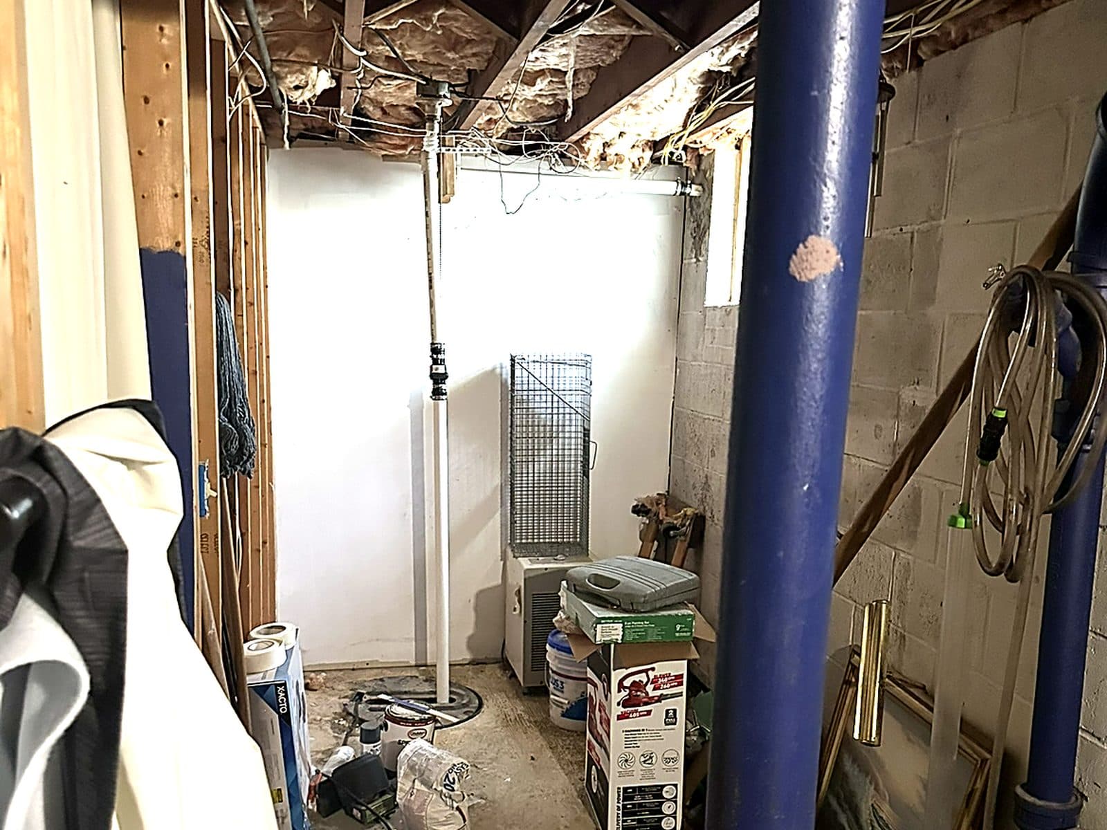 Unfinished basement with exposed wall framing, sagging insulation overhead and block walls